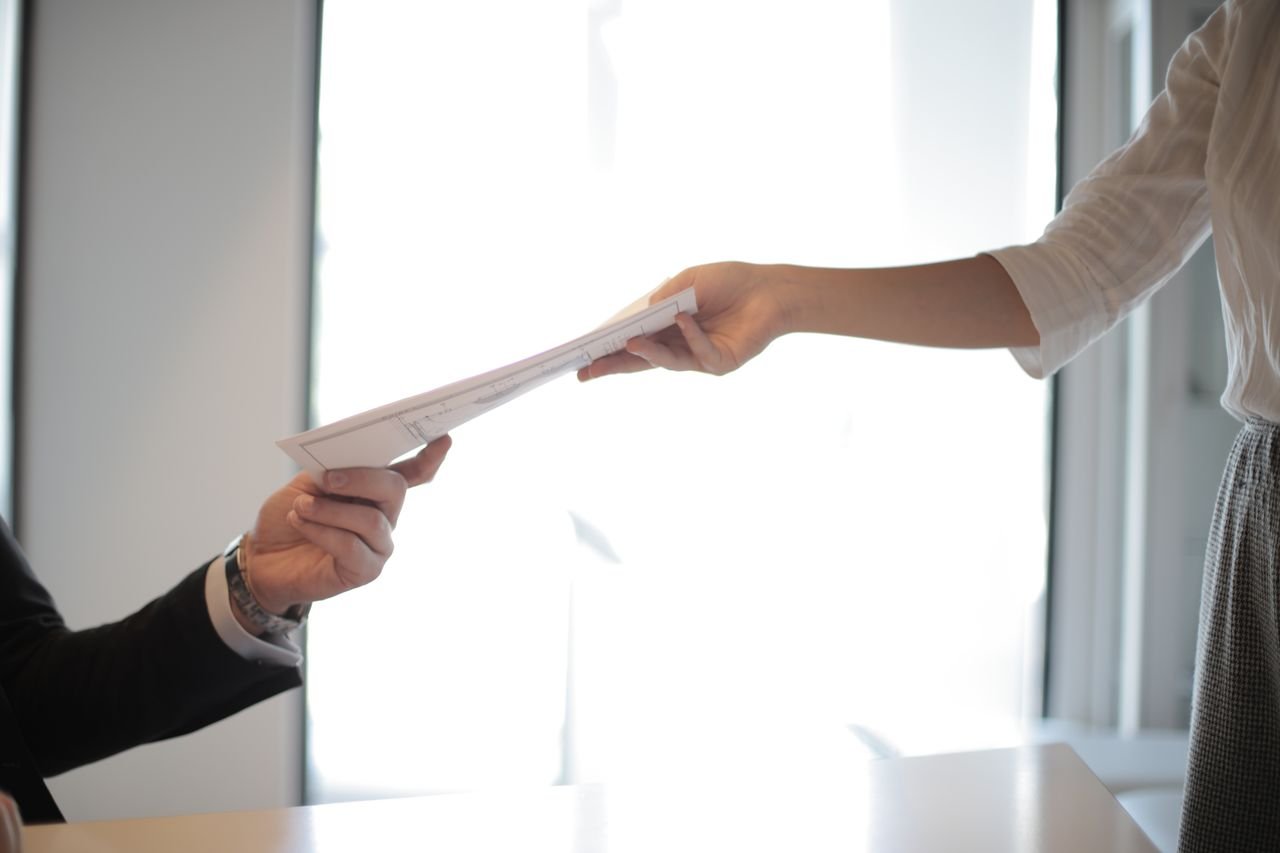 Mastering the First Impression: Your intriguing post title goes here Close-up of hands exchanging documents in a business setting indoors.